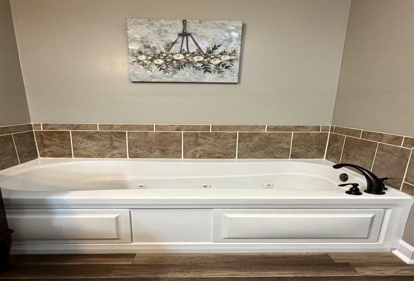 Full bathroom featuring a whirlpool tub and dark wood finished floors