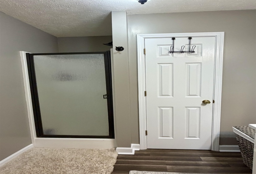 Full bathroom featuring a shower stall, a textured ceiling, and dark wood finished floors
