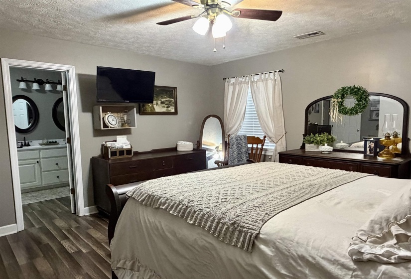 Bedroom with a textured ceiling, dark wood finished floors, a ceiling fan, and ensuite bathroom