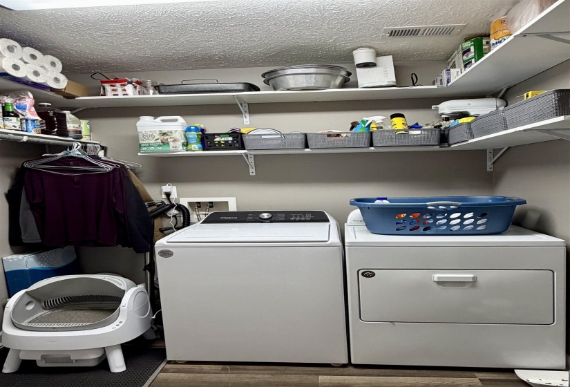 Laundry room with a textured ceiling, wood finished floors, and washing machine and clothes dryer