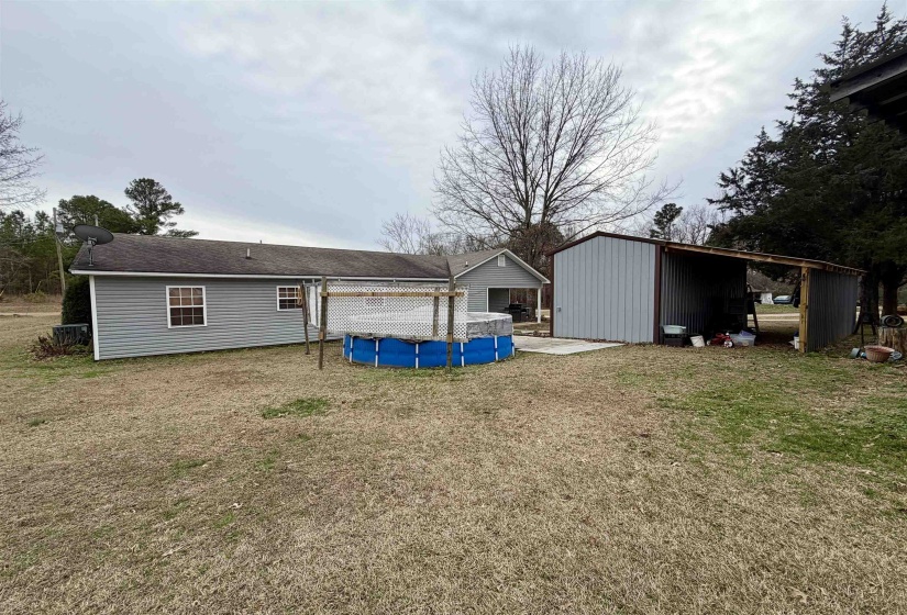 Back of house featuring a covered pool, a yard, a patio, and an outdoor structure