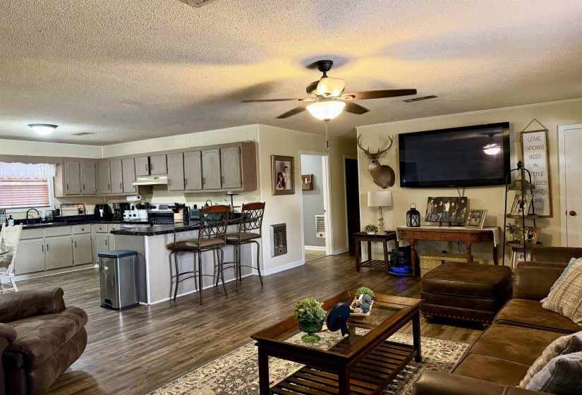 Living area with a textured ceiling, dark wood-style floors, ornamental molding, a ceiling fan, and heating unit