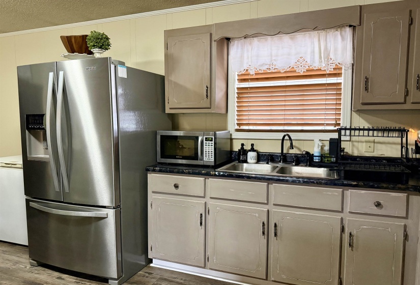 Kitchen with stainless steel appliances, dark wood-style flooring, dark stone counters, and a textured ceiling