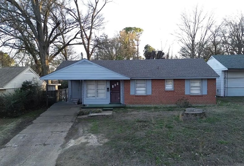 View of front facade featuring a front yard, a shingled roof, and brick siding