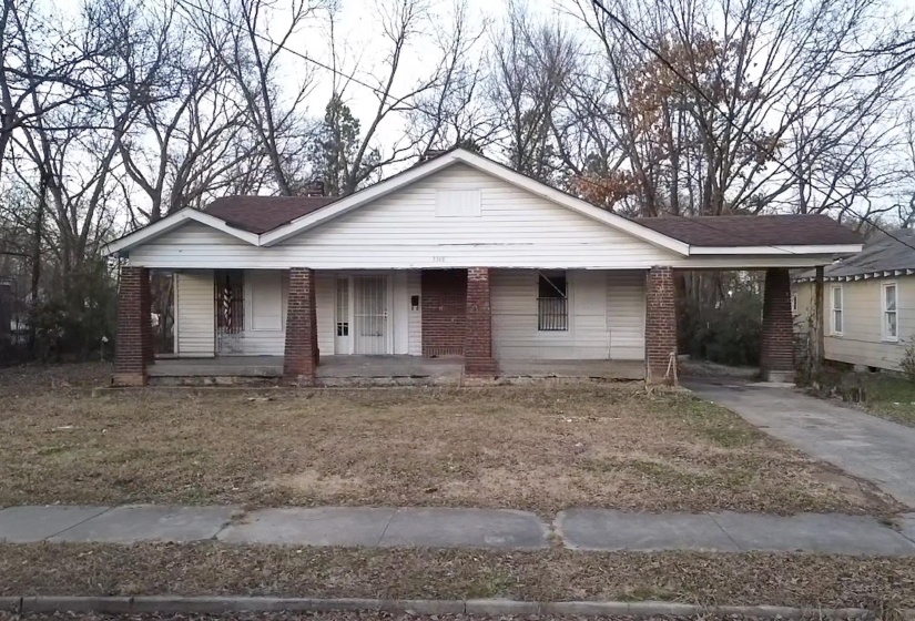 Bungalow-style house with a porch, an attached carport, brick siding, and driveway