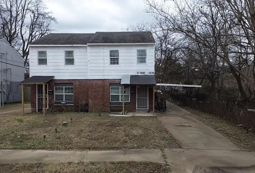 Traditional-style home featuring brick siding, driveway, and an attached carport