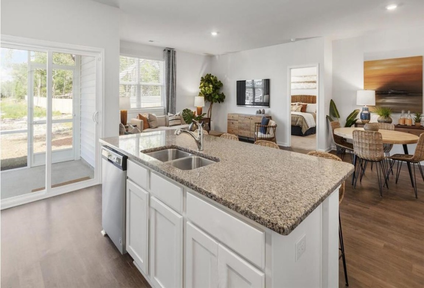 Kitchen with white cabinets, open floor plan, a kitchen island with sink, dishwasher, and light stone countertops