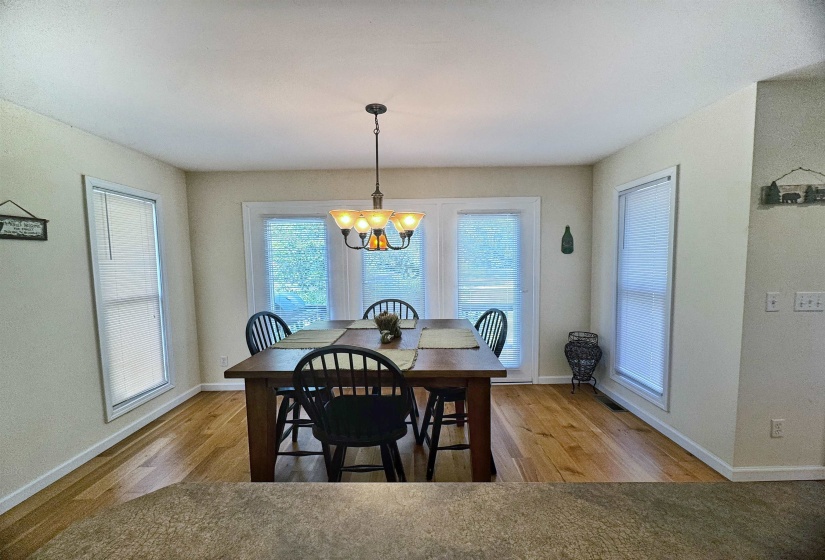 Dining area featuring wood-finish flooring, a central chandelier, and white trim