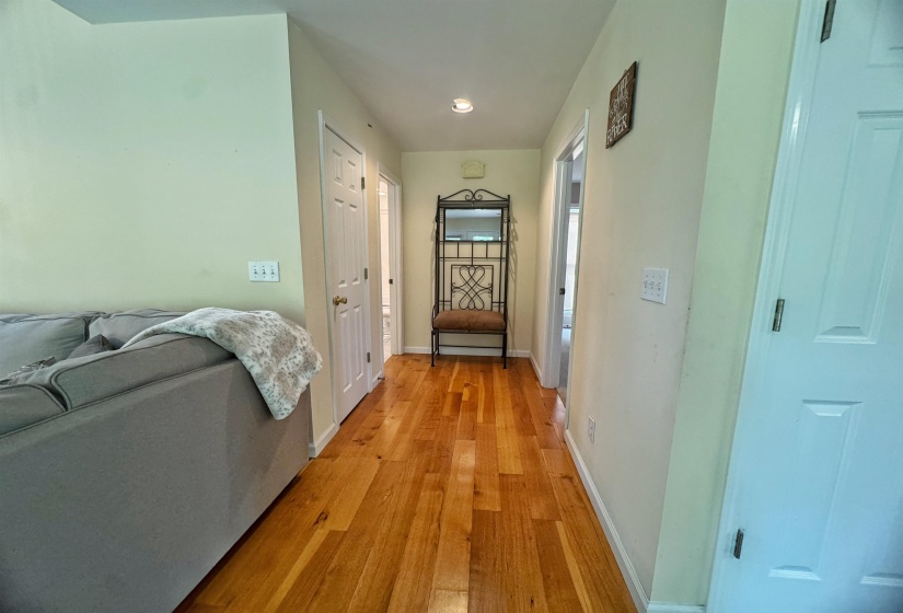 Hardwood flooring extends throughout this interior hallway, featuring recessed lighting and light-toned wall paint