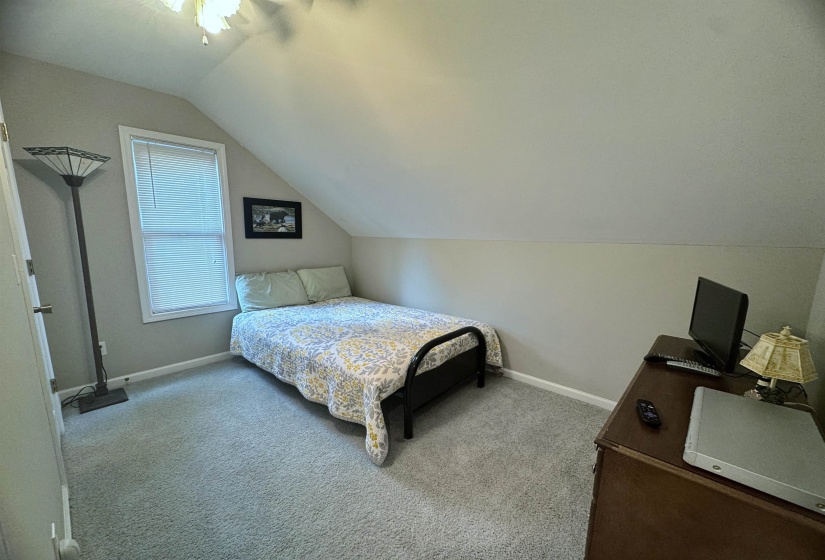 Carpeted room with sloped ceiling and window with blinds