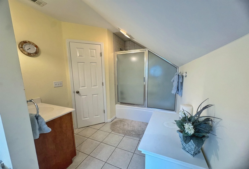 Bathroom with a shower-tub combination featuring a sliding frosted glass enclosure