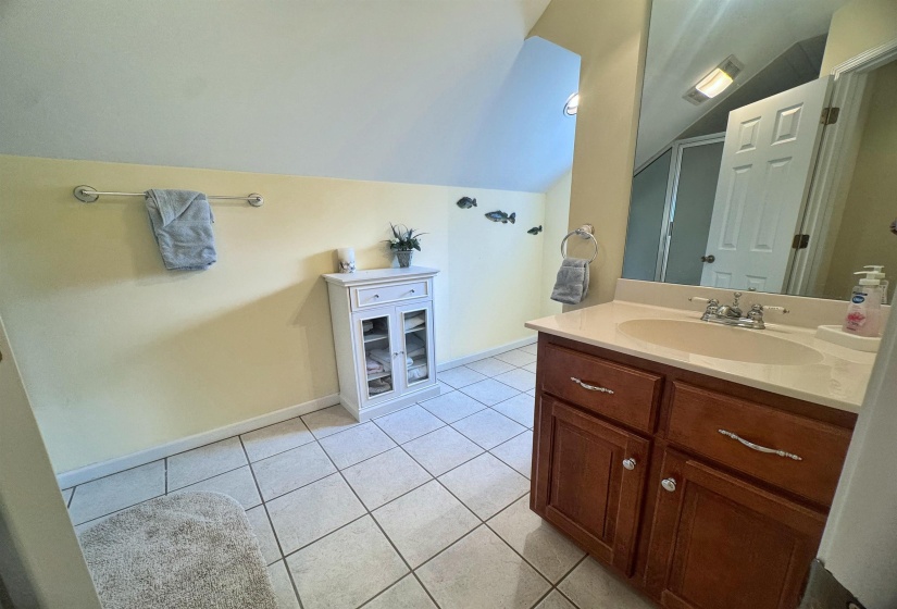 Bathroom featuring a wood-finish vanity with an integrated sink and light-toned countertop