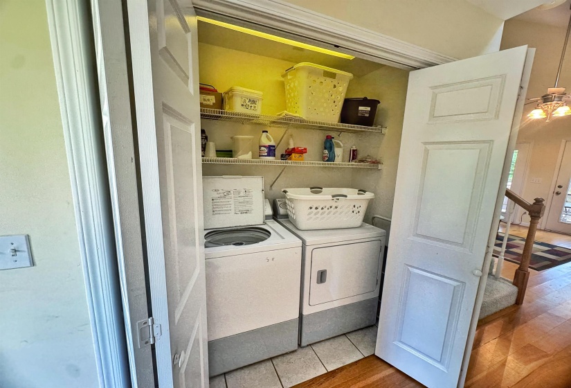 Dedicated laundry closet featuring a white top-load washing machine, a white dryer, and built-in wire shelving