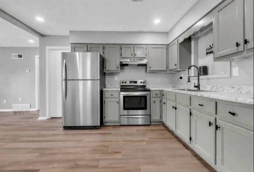 Kitchen featuring stainless steel appliances, recessed lighting, light wood-type flooring, a textured ceiling, and gray cabinets