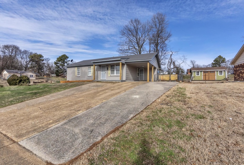 Ranch-style home featuring concrete driveway and a storage shed