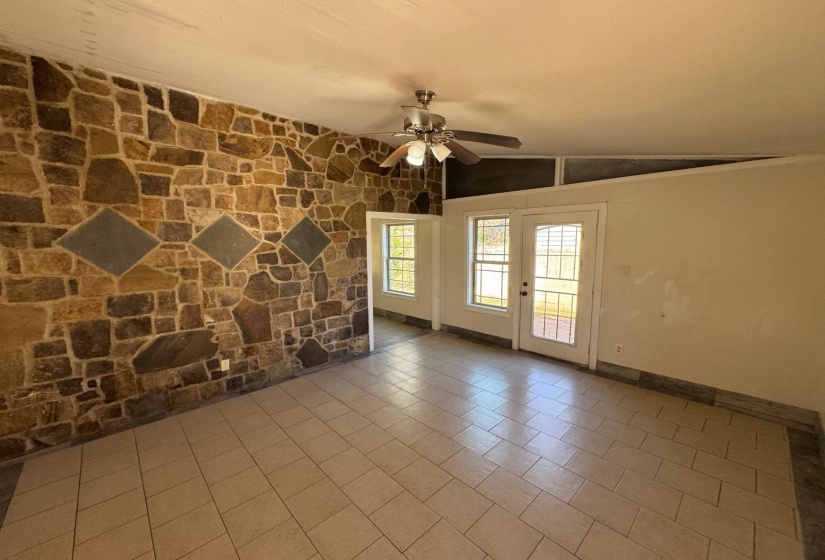 Empty room featuring lofted ceiling, tile patterned floors, and ceiling fan