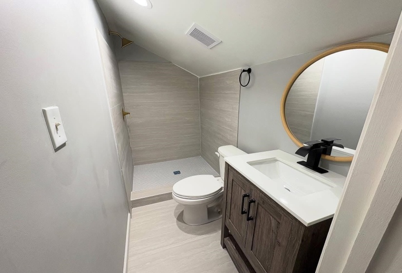 Bathroom featuring a shower stall, vanity, and lofted ceiling