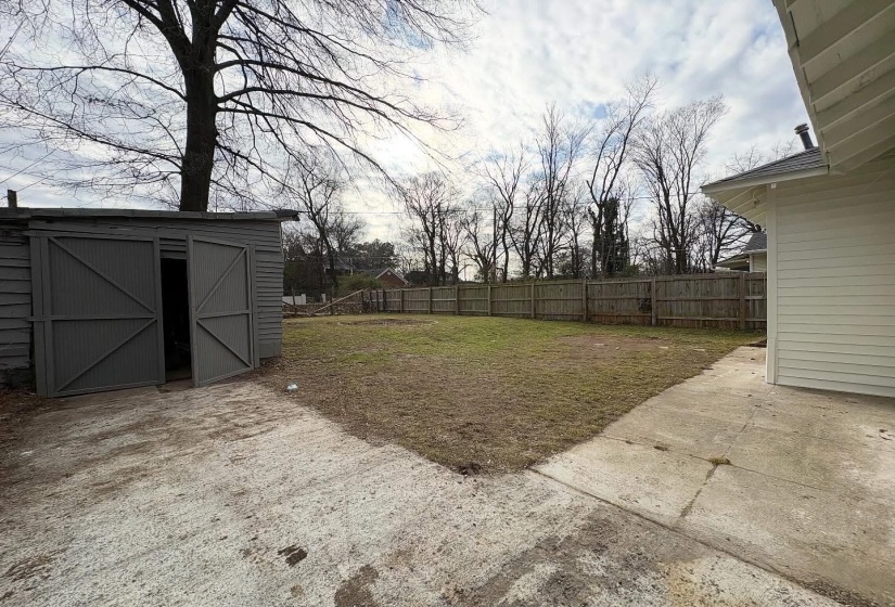 Fenced backyard featuring a patio and a storage unit