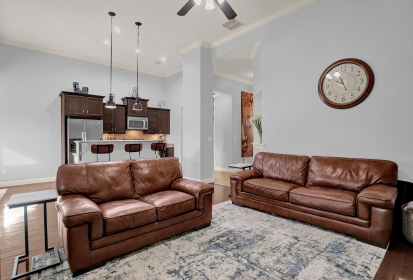 Living room featuring wood finished floors, ornamental molding, and a ceiling fan