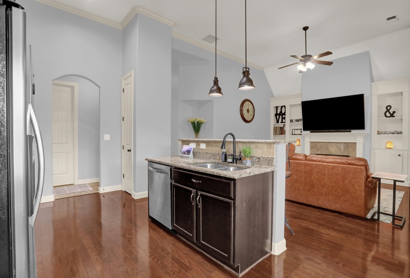 Kitchen with arched walkways, stainless steel appliances, light stone countertops, hanging light fixtures, and ceiling fan