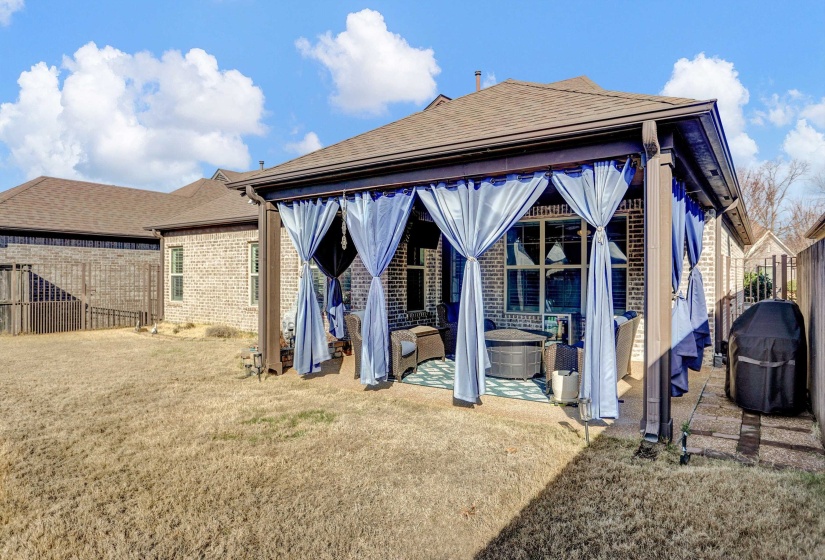 Back of property with a fenced backyard, a patio, roof with shingles, and brick siding