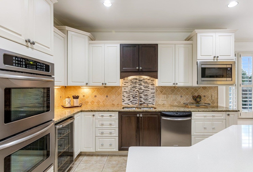 Kitchen with appliances with stainless steel finishes, white cabinetry, light stone countertops, light tile patterned floors, and wine cooler