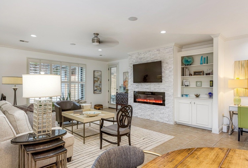 Living room with crown molding, a stone fireplace, light tile patterned floors, ceiling fan, and recessed lighting