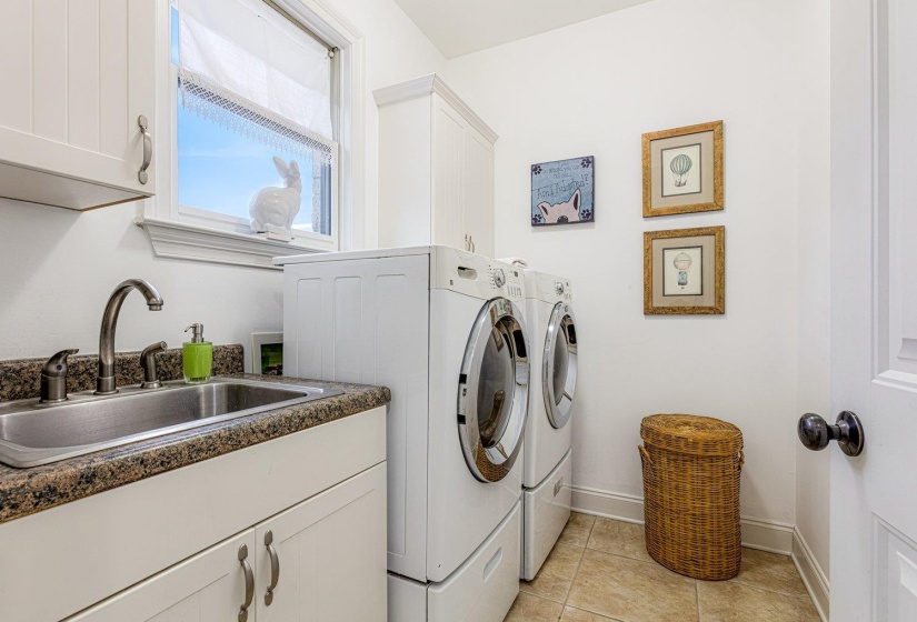 Laundry room featuring washing machine and clothes dryer, cabinet space, and light tile patterned floors