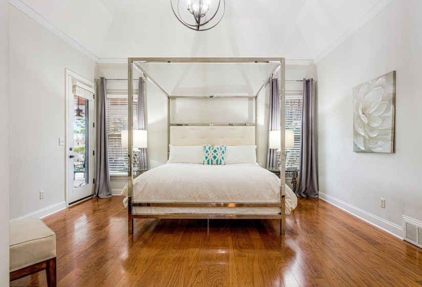 Bedroom with ornamental molding, access to exterior, lofted ceiling, wood-type flooring, and multiple windows