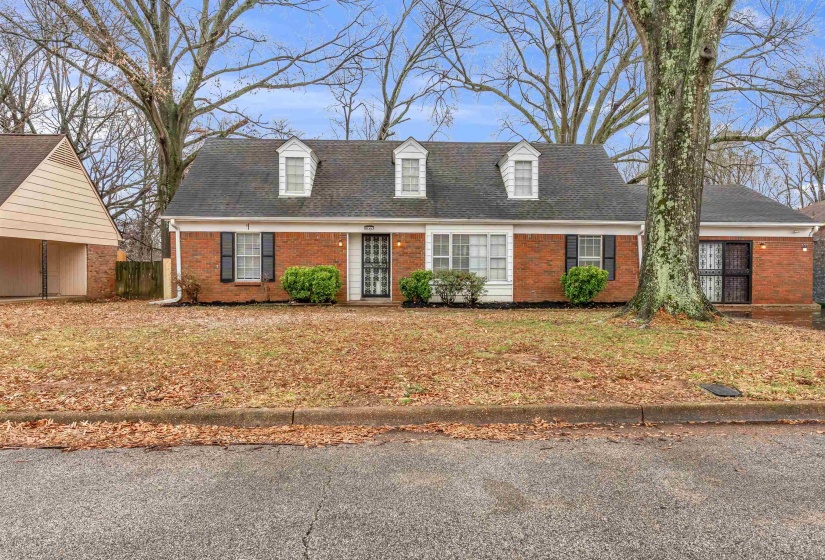 New england style home featuring brick siding and roof with shingles