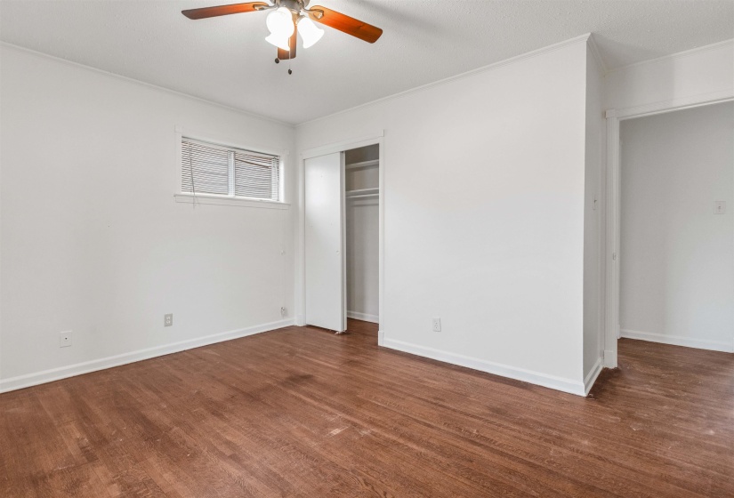 Unfurnished bedroom with dark wood-style floors, a ceiling fan, and a closet