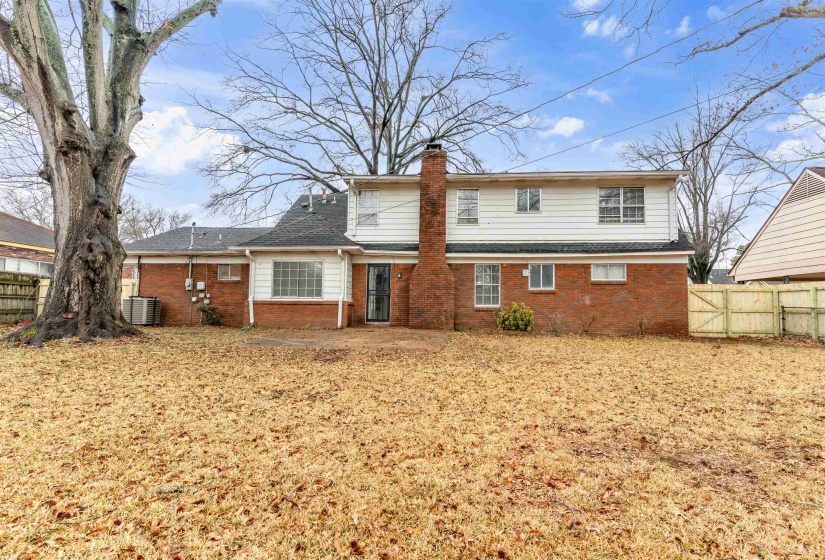 Rear view of property with a fenced backyard, a chimney, brick siding, and a shingled roof