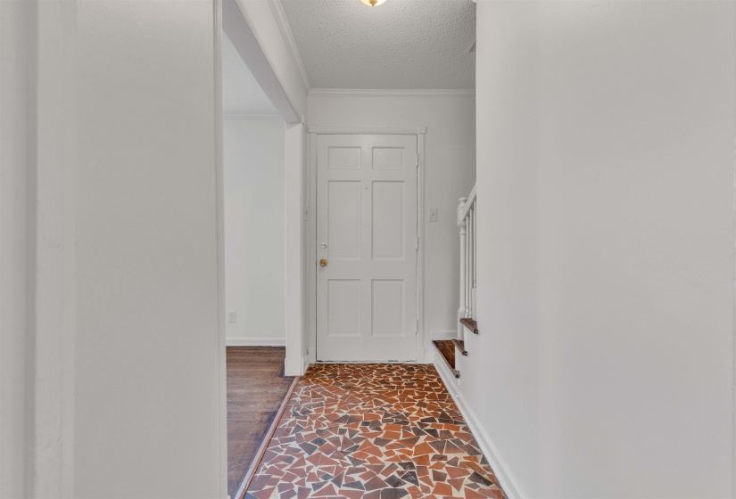 Corridor featuring a textured ceiling, ornamental molding, and dark stone finish flooring