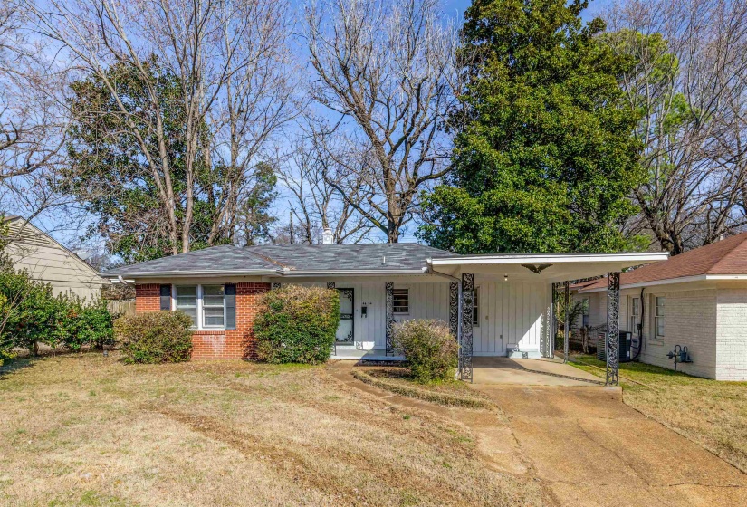 Ranch-style home featuring an attached carport, a front yard, concrete driveway, brick siding, and board and batten siding
