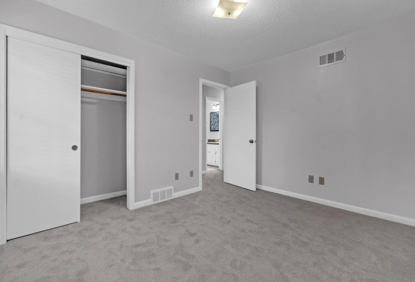 Unfurnished bedroom featuring light carpet, a textured ceiling, and a closet