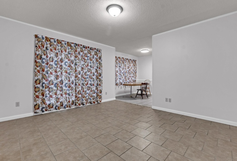 Unfurnished room with a textured ceiling, crown molding, and light tile patterned flooring