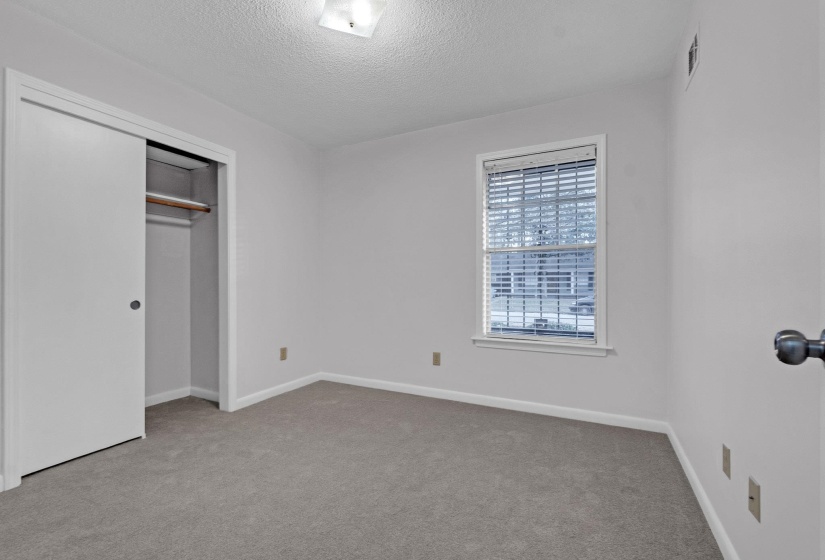 Unfurnished bedroom with light colored carpet, a closet, and a textured ceiling