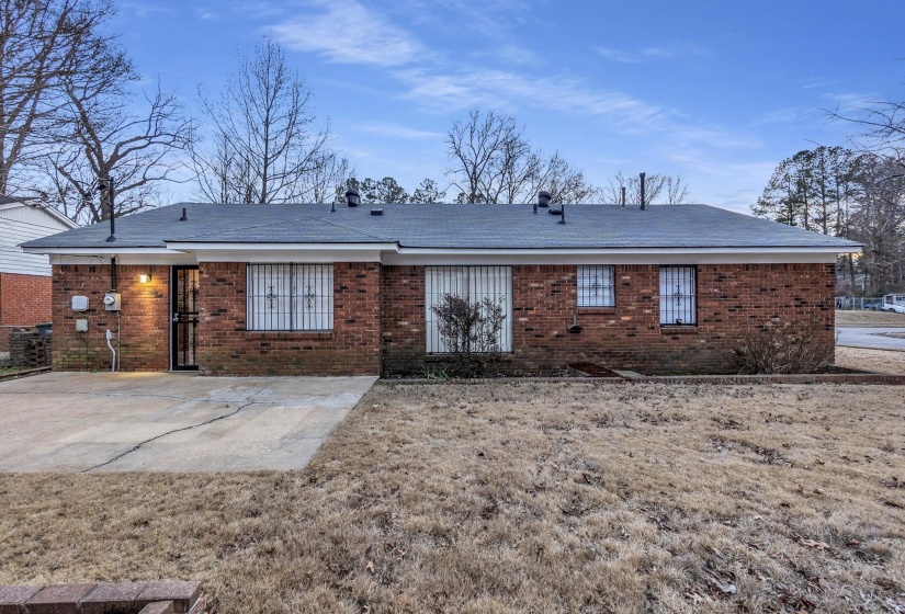 Rear view of house with a patio area, brick siding, and a yard