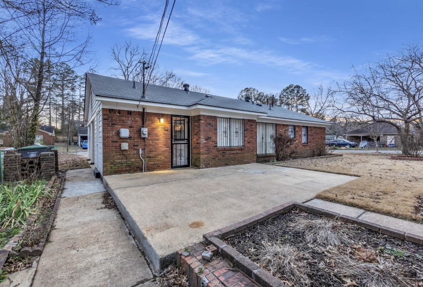 Rear view of property with brick siding, a patio area, and a shingled roof