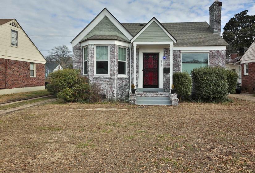 View of front of home featuring a chimney, roof with shingles, a front yard, and brick siding