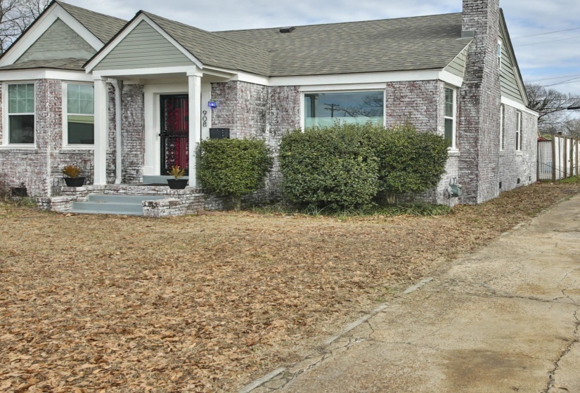 View of front of property featuring roof with shingles, a chimney, brick siding, and a front lawn