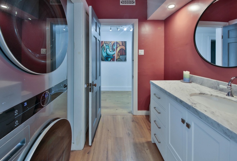 Bathroom with vanity, light wood-style floors, stacked washer and clothes dryer, and recessed lighting