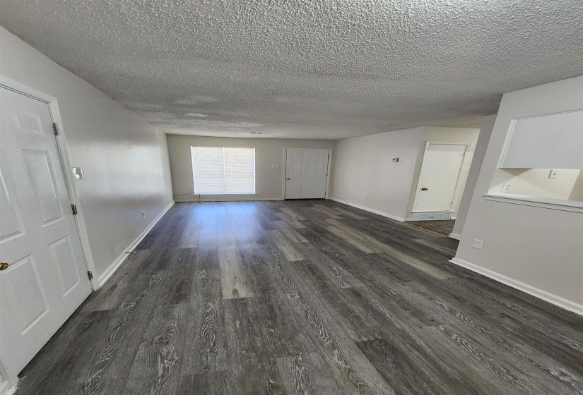 Unfurnished living room featuring a textured ceiling and dark hardwood / wood-style flooring