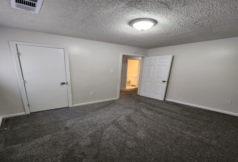Unfurnished bedroom featuring a textured ceiling and carpet floors