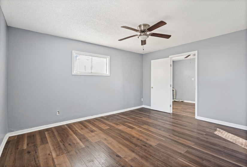 Empty room with dark wood-style floors, a textured ceiling, and a ceiling fan