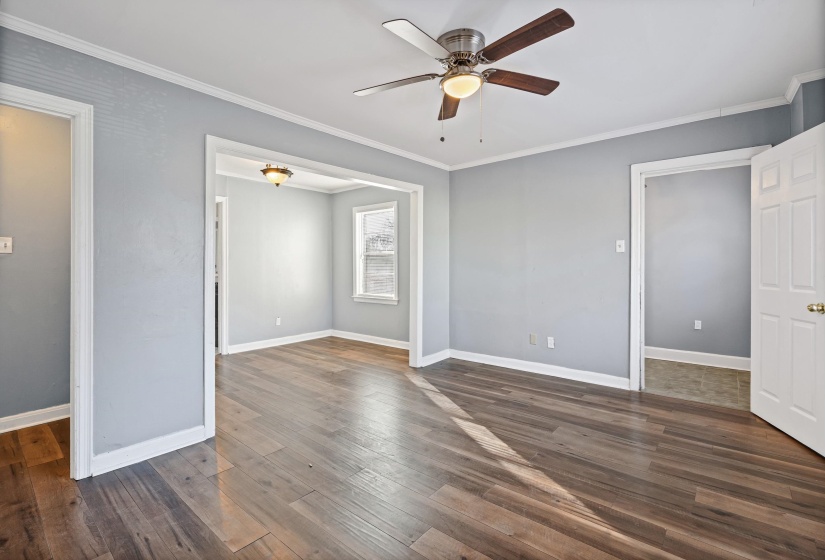Unfurnished bedroom featuring ornamental molding, a ceiling fan, and dark wood finished floors