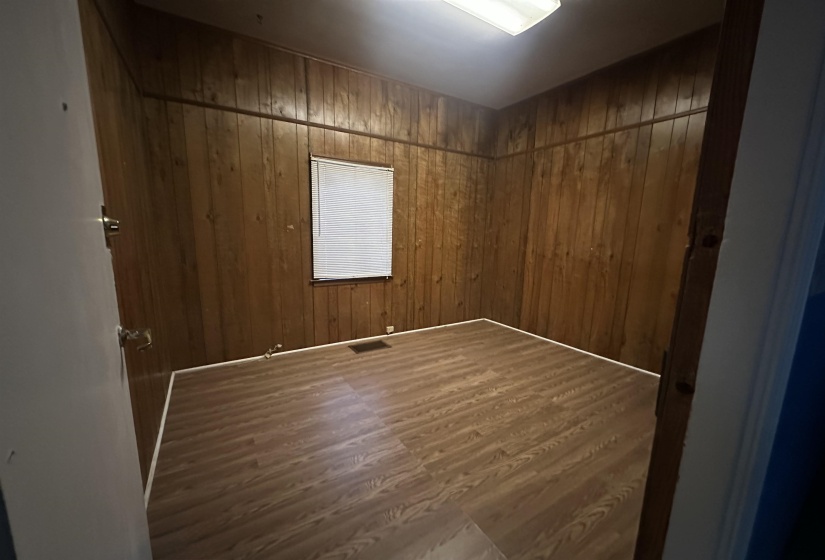Unfurnished room with wooden walls and dark wood-type flooring