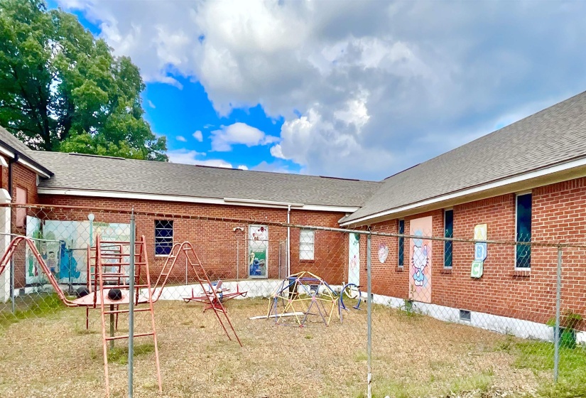 Back of house featuring roof with shingles, brick siding, and a yard