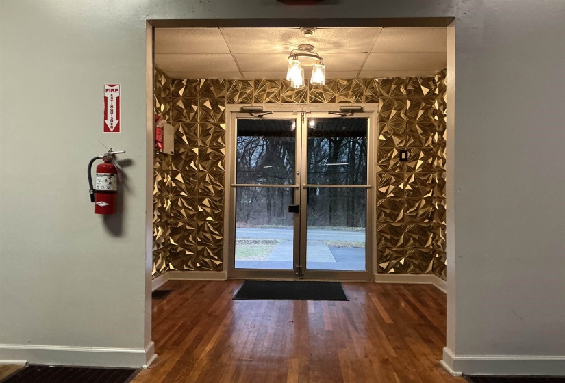 Entryway with wood finished floors, an accent wall, a paneled ceiling, and french doors