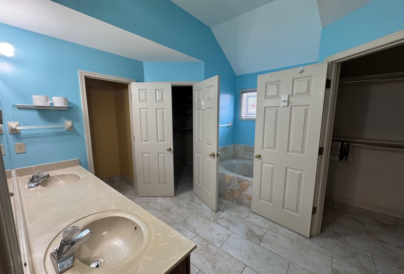 Full bath with a spacious closet, a garden tub, double vanity, and lofted ceiling